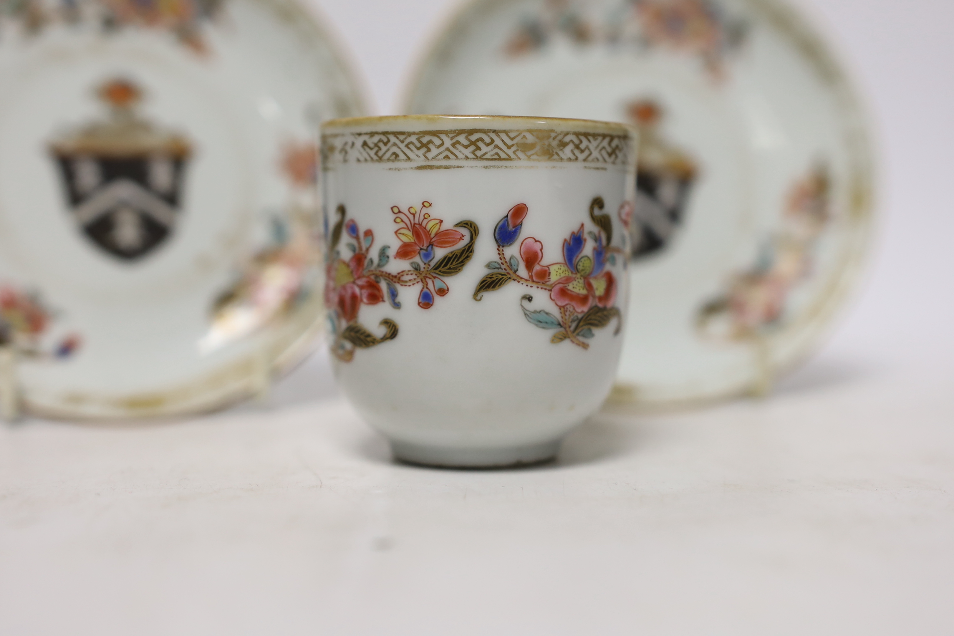A Chinese armorial coffee cup and two saucers, saucers 12cm in diameter